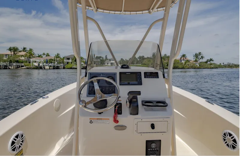 Slide: The Image of 2023 Scout 195 Sportfish boat console with steering wheel, controls, and water view. - 7