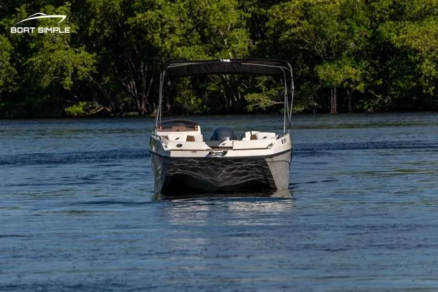 Slide: The Image of 2023 Starcraft SVX 231 OB DH boat on a serene lake with lush greenery. - 2