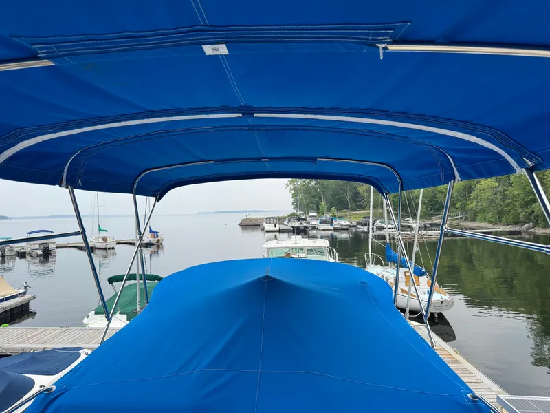 Slide: The Image of 1981 Marine Trader 34 Double Cabin with blue canopy docked at a marina. - 32