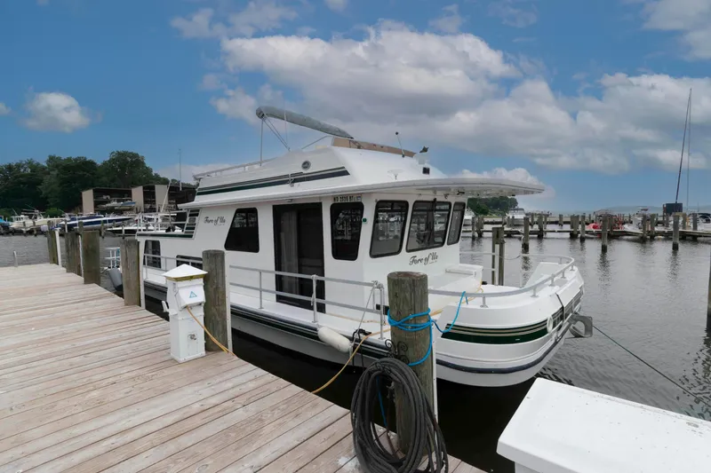 The Image of Gibson 47 Classic 2004 houseboat docked at marina under cloudy sky. - 0