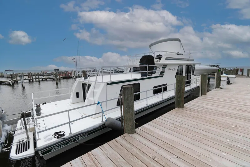 Slide: The Image of Houseboat docked at marina, Gibson 47 Classic, 2004 model, under a partly cloudy sky. - 1