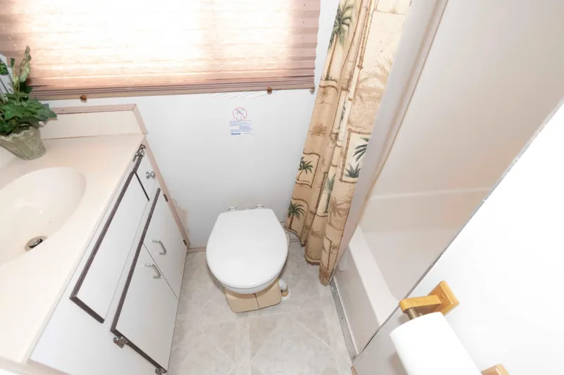 Slide: The Image of Compact bathroom in a 2004 Gibson 47 Classic boat, featuring a toilet, sink, and shower. - 17