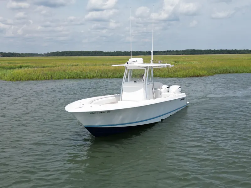 Slide: The Image of 2022 Contender 30 ST boat on calm water with grassy shoreline background. - 1