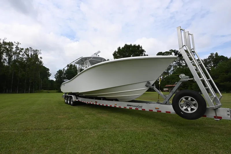 Slide: The Image of 2017 Yellowfin 36 boat on trailer, parked on grassy field with trees in background. - 6