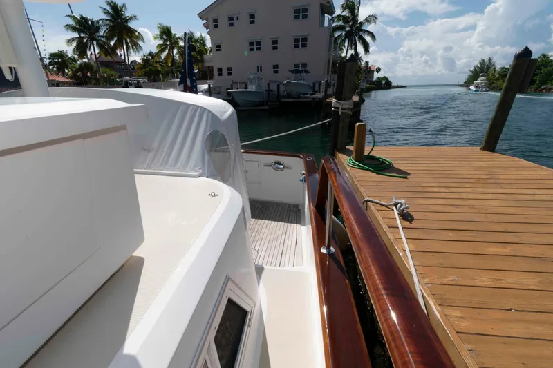 Slide: The Image of 1999 Ocean Alexander 486/510 Classico yacht docked by a wooden pier, with palm trees in the background. - 16