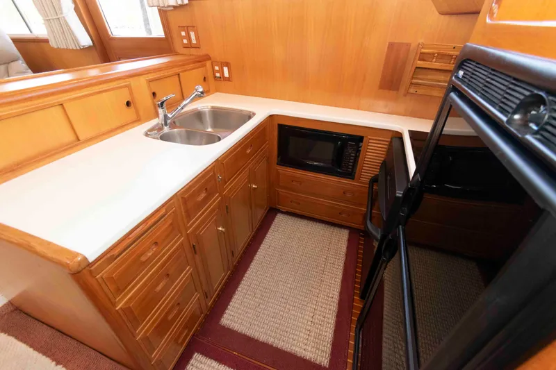 Slide: The Image of 1999 Ocean Alexander 486/510 Classico yacht kitchen with sink, microwave, and wooden cabinetry. - 33