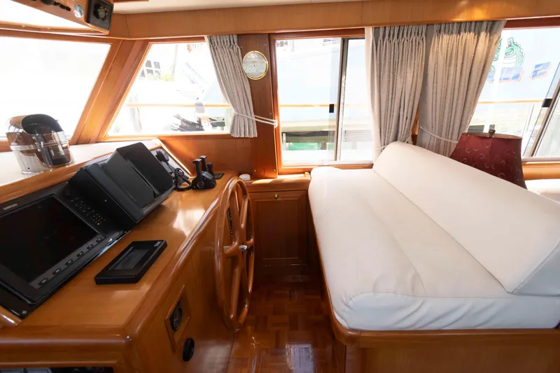 Slide: The Image of 1999 Ocean Alexander 486/510 Classico yacht interior with helm, wooden wheel, and cushioned seating. - 35