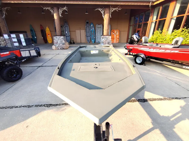 Slide: The Image of 2026 Tracker GRIZZLY 1648 AWL boat displayed outdoors with kayaks and other boats. - 2