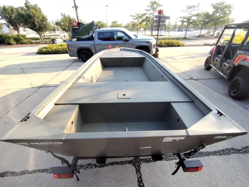 Slide: The Image of 2026 Tracker GRIZZLY 1648 AWL boat on trailer, parked outdoors near vehicles. - 3