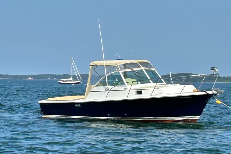 The Image of 2003 Surf-Hunter 25 boat on calm blue water with distant sailboats. - 0