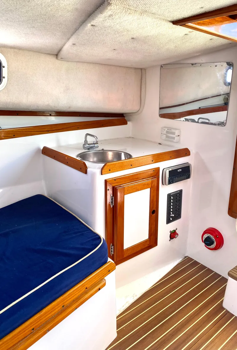 Slide: The Image of Interior of 2003 Surf-Hunter 25 boat with sink, wooden cabinetry, and blue cushioned seating. - 10