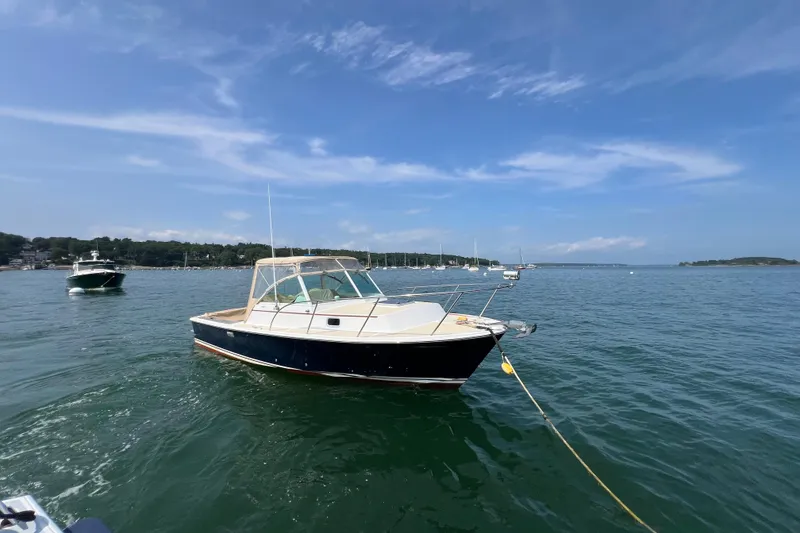 Slide: The Image of 2003 Surf-Hunter 25 boat anchored on calm water under a clear blue sky. - 13