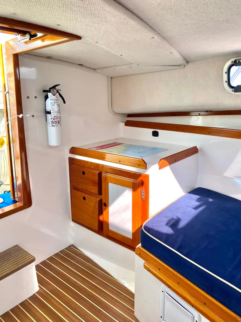 Slide: The Image of Interior of a 2003 Surf-Hunter 25 boat with wooden cabinetry and blue seating. - 6