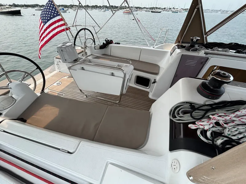 Slide: The Image of 2019 Jeanneau Sun Odyssey 419 sailboat cockpit with American flag, docked in marina. - 2