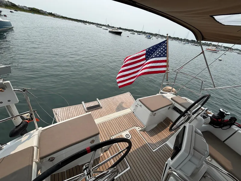 Slide: The Image of 2019 Jeanneau Sun Odyssey 419 sailboat with American flag, docked in a serene harbor. - 3