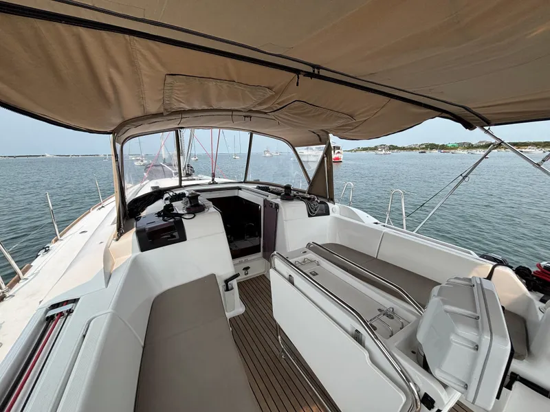 Slide: The Image of 2019 Jeanneau Sun Odyssey 419 sailboat cockpit with canopy, docked in a serene harbor. - 45