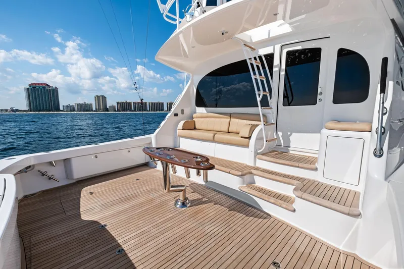 Slide: The Image of 2017 Viking 62 Enclosed Bridge yacht deck with seating, ocean view, and city skyline. - 13