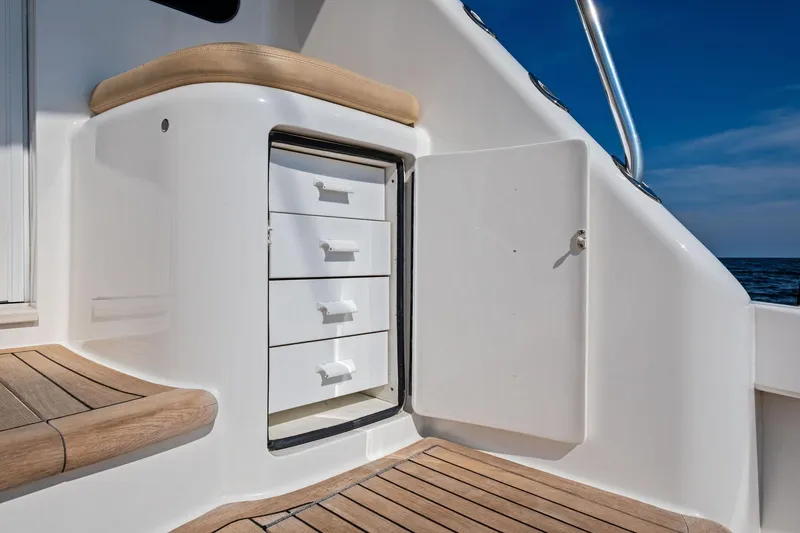 Slide: The Image of 2017 Viking 62 Enclosed Bridge yacht interior with open storage drawers and wooden flooring. - 18