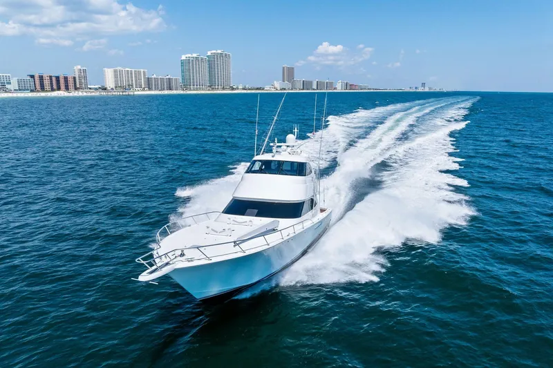 Slide: The Image of 2017 Viking 62 Enclosed Bridge yacht cruising near a coastal city skyline. - 69