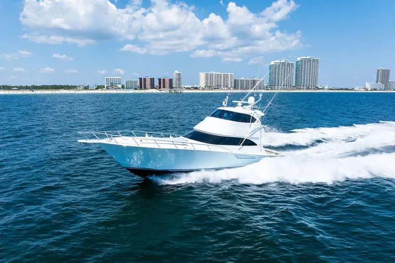 Slide: The Image of 2017 Viking 62 Enclosed Bridge yacht cruising near a coastal city skyline. - 70