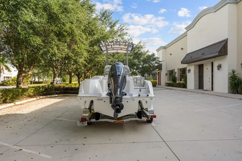 Slide: The Image of 2025 Sea Fox 228 Commander boat parked in a sunny lot with trees and buildings. - 4