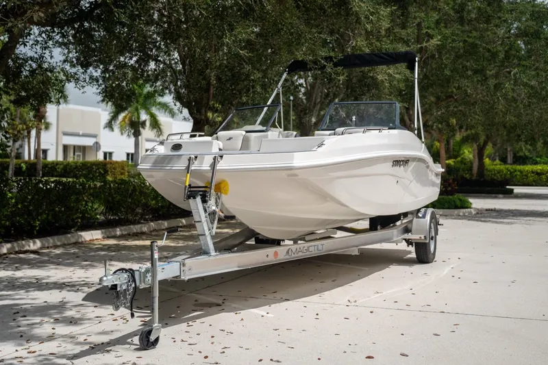 Slide: The Image of 2022 Starcraft SVX 190 DC boat on trailer, parked outdoors with trees in background. - 7