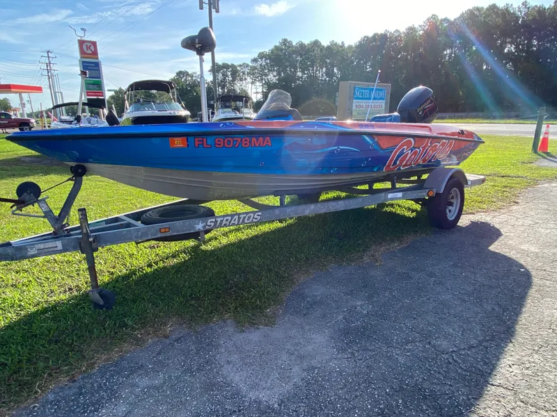 Slide: The Image of 1999 Stratos 283 boat on trailer, vibrant blue design, parked near a gas station. - 2