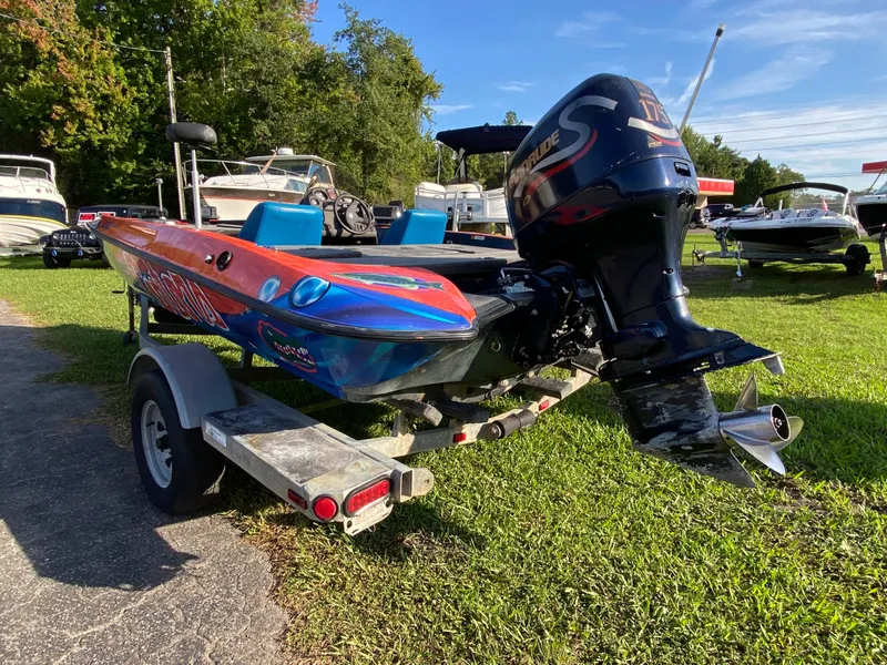 Slide: The Image of 1999 Stratos 283 boat with Evinrude motor on trailer, parked on grass. - 3