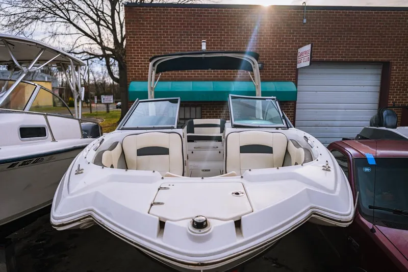 Slide: The Image of 2018 Chaparral 224 Sunesta boat with open bow seating, parked near a brick building. - 1