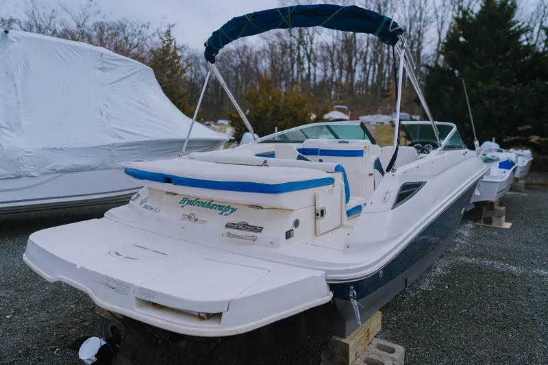 Slide: The Image of 2013 Sea Ray 220 Sundeck boat on blocks, featuring a blue canopy and white seating. - 3