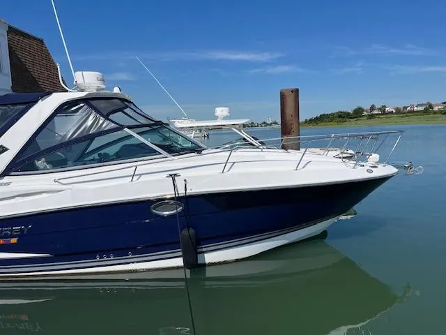 The Image of 2022 Monterey 295 Sport Yacht docked on calm water under clear blue sky. - 0