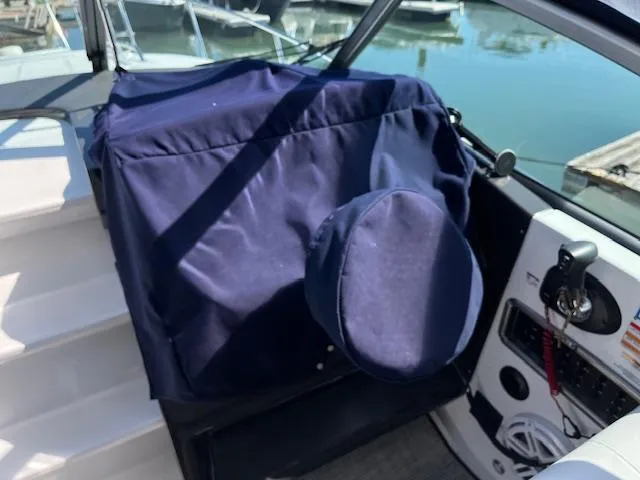 Slide: The Image of 2022 Monterey 295 Sport Yacht helm with blue cover, docked at marina. - 14