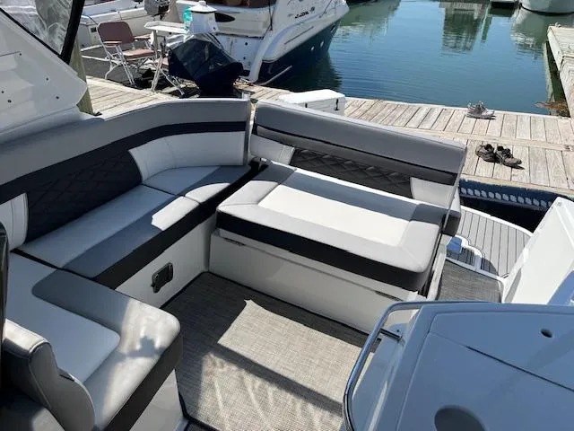 Slide: The Image of 2022 Monterey 295 Sport Yacht interior with plush seating at a marina dock. - 18