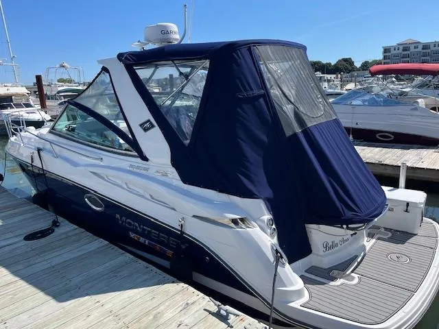 Slide: The Image of 2022 Monterey 295 Sport Yacht docked, featuring a sleek design and navy blue canopy. - 2