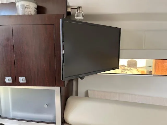 Slide: The Image of Interior of 2022 Monterey 295 Sport Yacht with mounted TV and wooden cabinetry. - 22