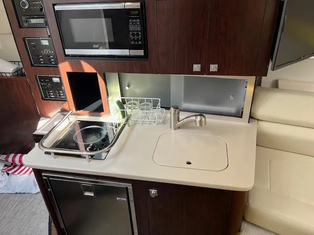 Slide: The Image of 2022 Monterey 295 Sport Yacht kitchen with microwave, stove, sink, and fridge. - 23