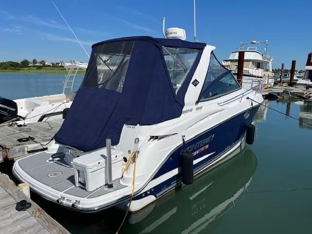 Slide: The Image of 2022 Monterey 295 Sport Yacht docked in a marina, featuring a sleek design and blue canopy. - 3