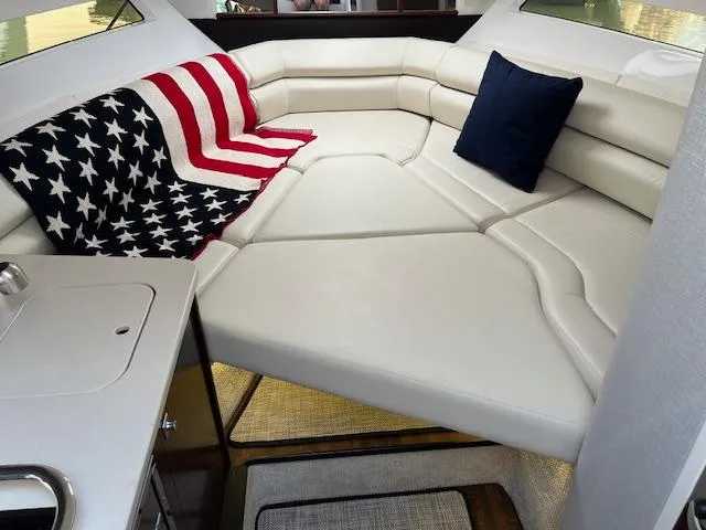 Slide: The Image of 2022 Monterey 295 Sport Yacht interior with American flag blanket and white seating. - 33
