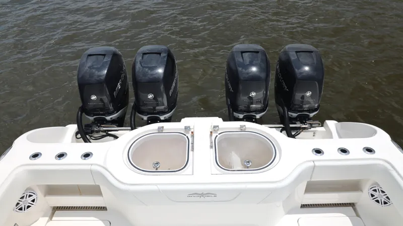 Slide: The Image of Four powerful outboard engines on a 2018 Invincible 40 Catamaran, docked on water. - 29