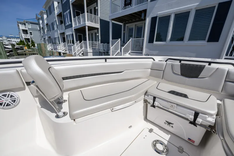Slide: The Image of 2019 Wellcraft 352 Fisherman boat interior with seating and cooler, docked near modern buildings. - 13