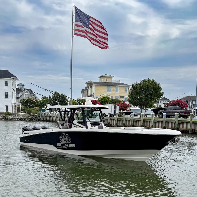 Slide: The Image of 2019 Wellcraft 352 Fisherman boat on water, American flag in background, coastal houses nearby. - 2