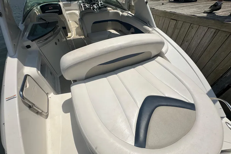 Slide: The Image of 2011 Chaparral 287 SSX boat interior with white and navy seating, docked by wooden pier. - 14