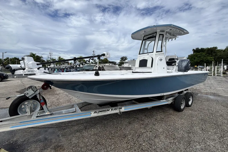 Slide: The Image of 2026 Tidewater 2410 Bay Max boat on trailer, parked outdoors under cloudy sky. - 2