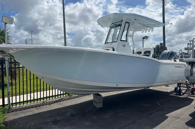 Slide: The Image of 2025 Tidewater 232 LXF boat displayed outdoors under cloudy sky. - 2