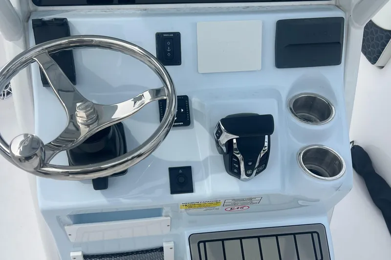 Slide: The Image of 2025 Tidewater 232 LXF boat console with steering wheel, controls, and cup holders. - 3