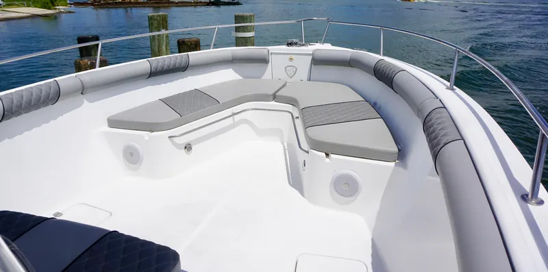 Slide: The Image of Century 3100 boat's spacious deck with cushioned seating, docked by serene waters, year 2000 model. - 6