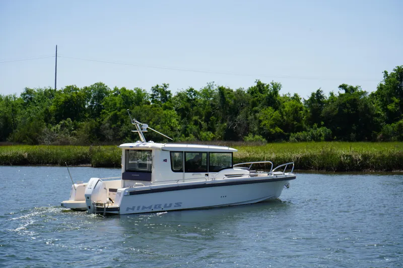 Slide: The Image of 2024 Nimbus Commuter9 C9 boat cruising on a calm river with lush greenery. - 6