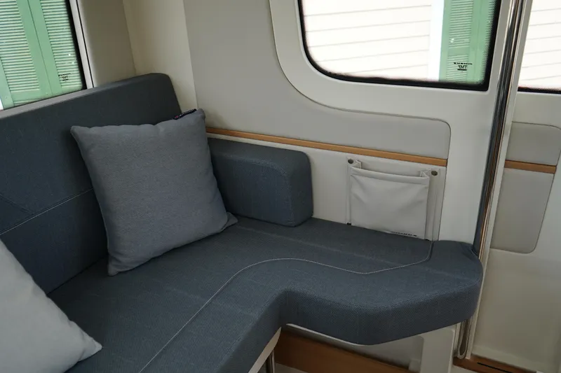 Slide: The Image of 2024 Nimbus Commuter9 C9 interior with gray cushioned seating and window view. - 16