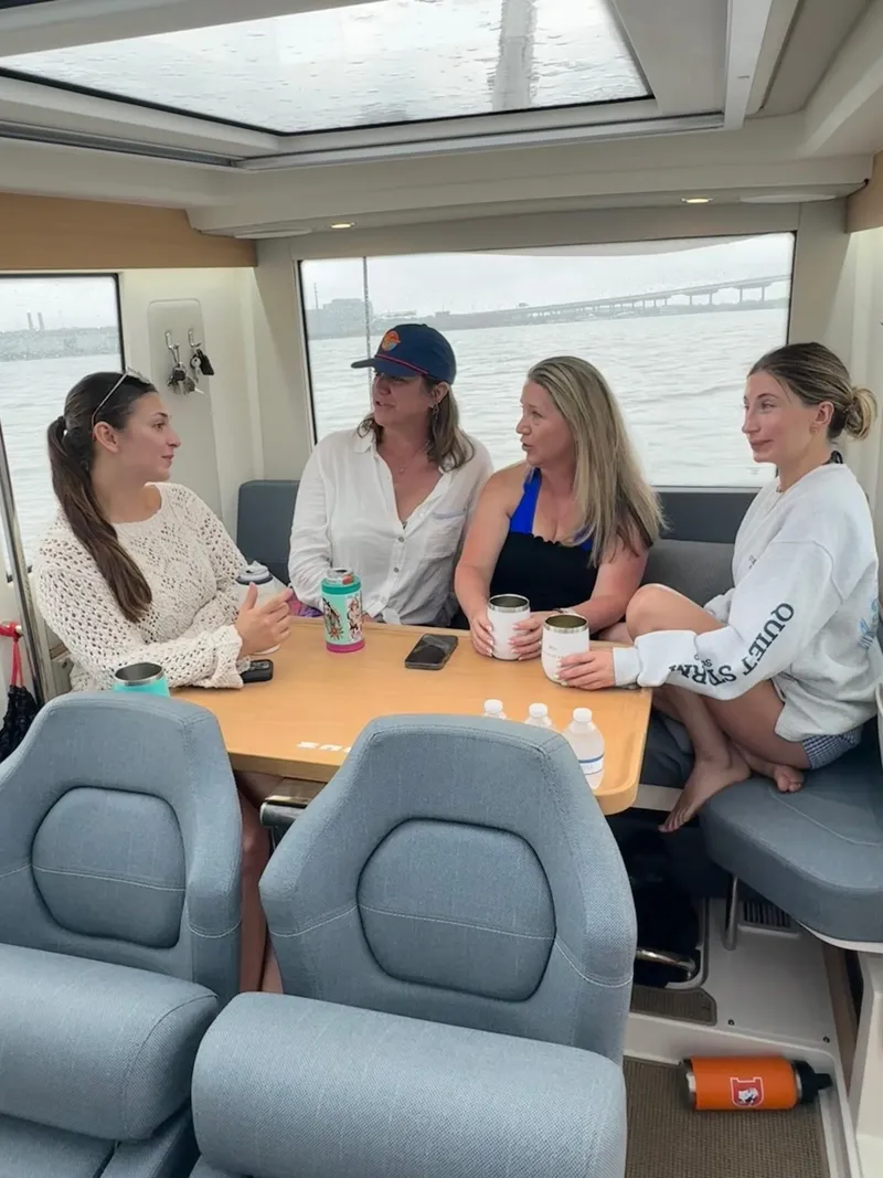Slide: The Image of Four people conversing inside a 2024 Nimbus Commuter9 C9 boat cabin. - 23