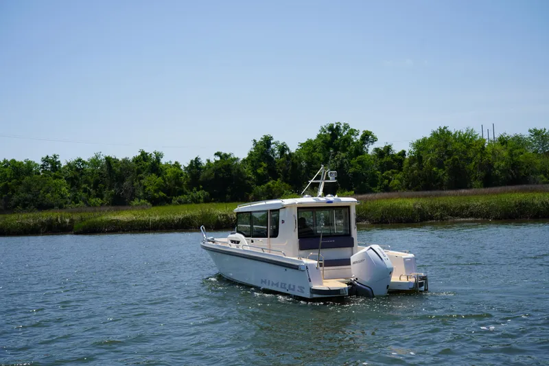 Slide: The Image of 2024 Nimbus Commuter9 C9 boat cruising on a scenic river with lush greenery. - 4